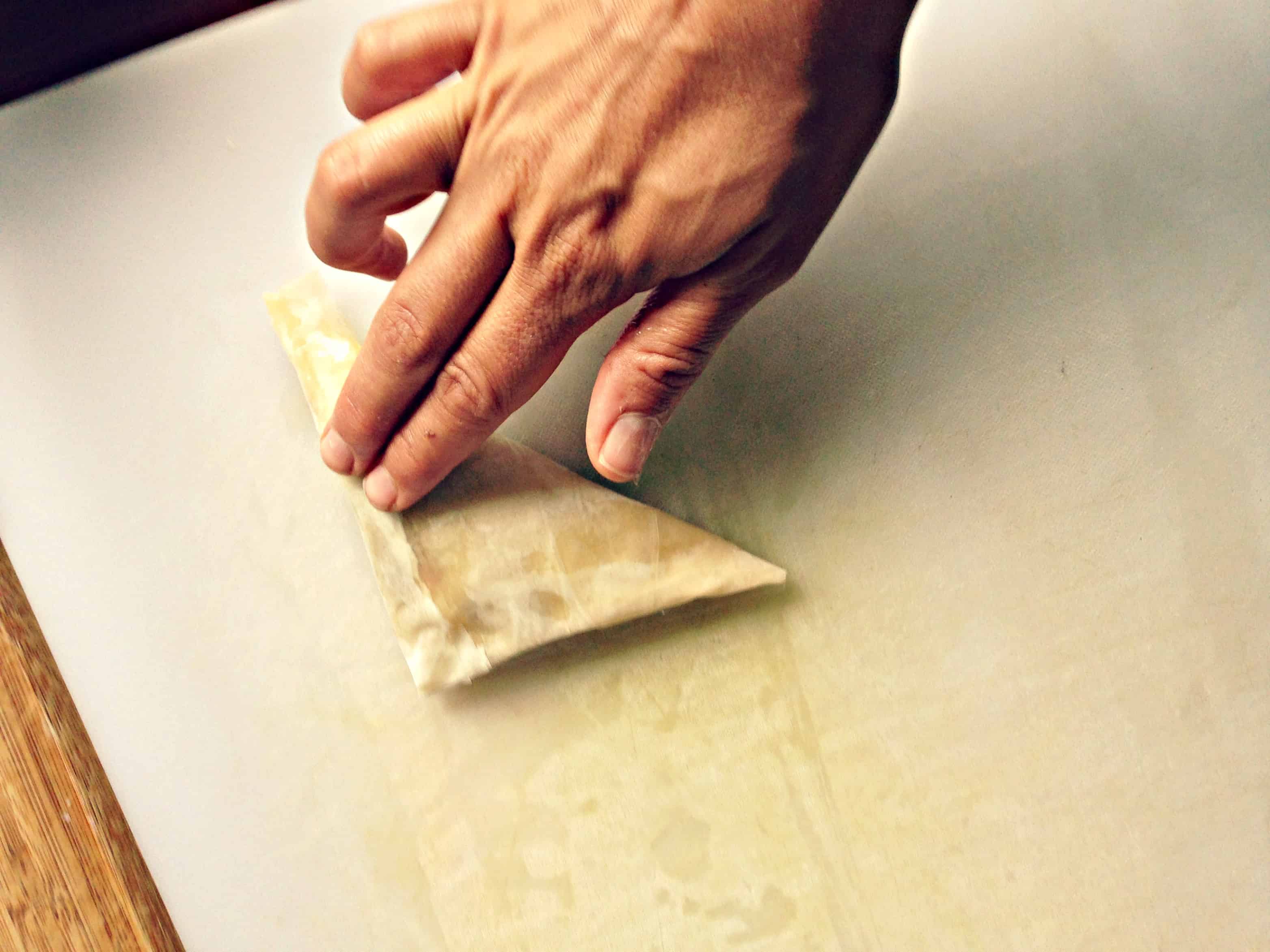 Sealing the edges of puff pastry with fingertips.