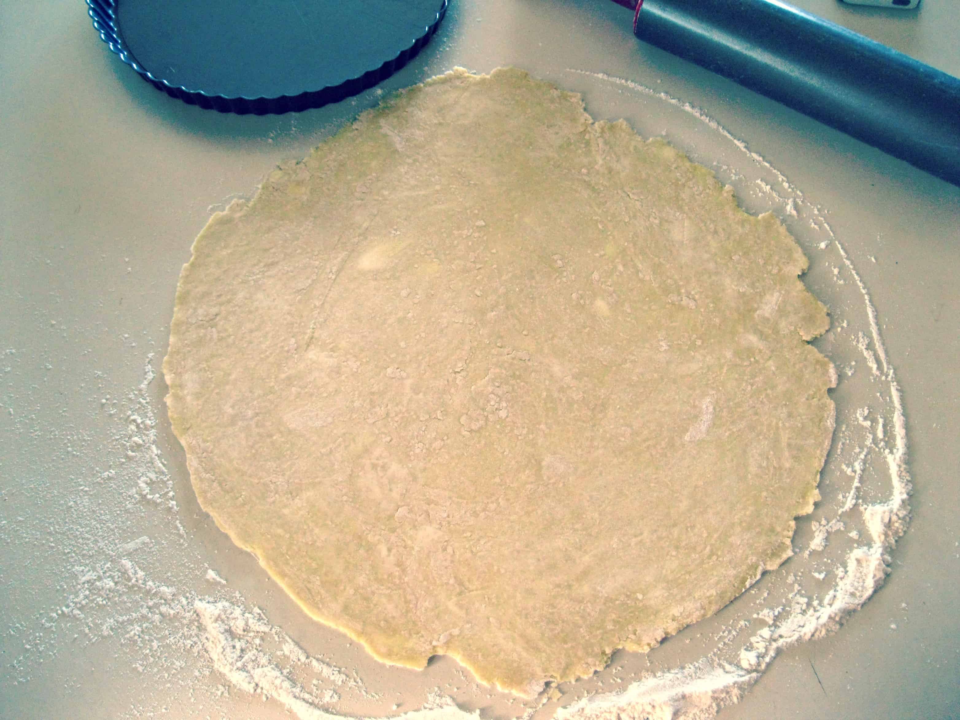 Pie dough rolled out in a circle on a floured counter.