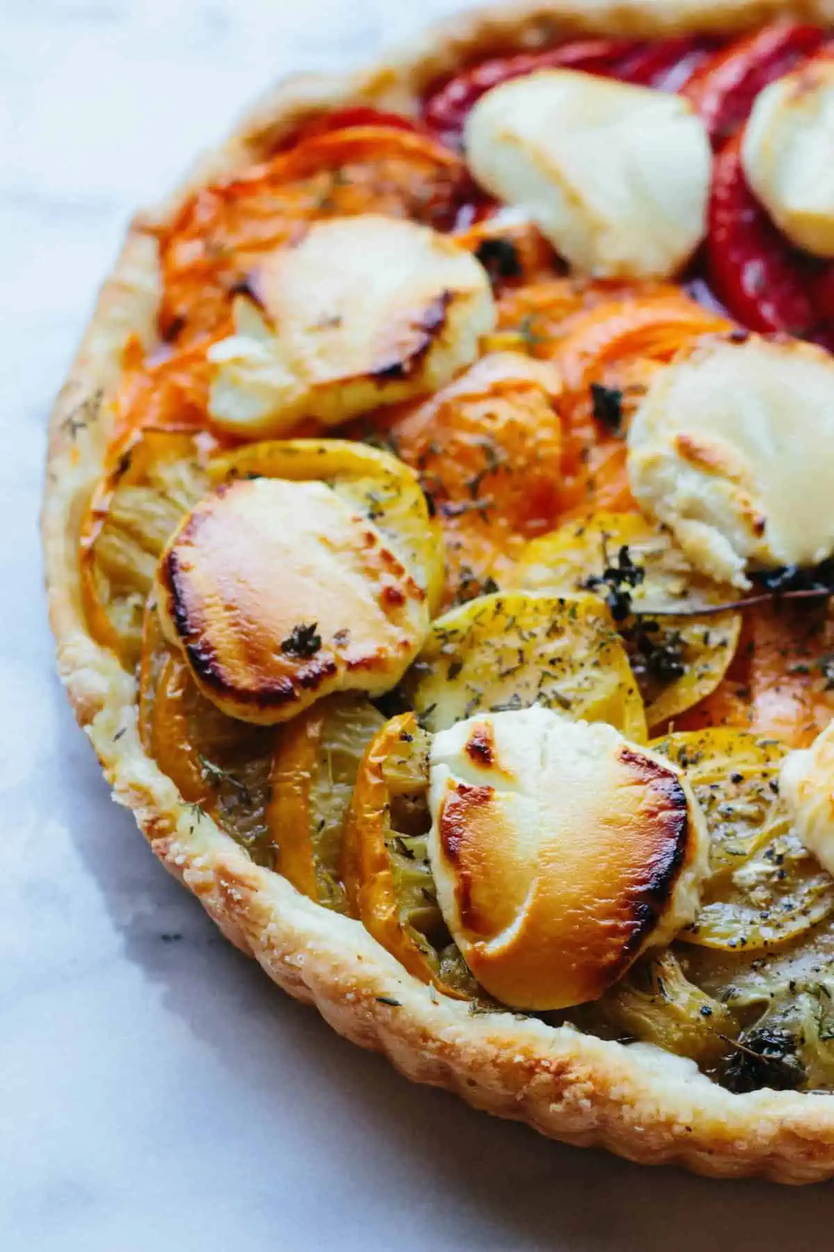 Close up of roasted tomatoes and goat cheese in a tart shell.