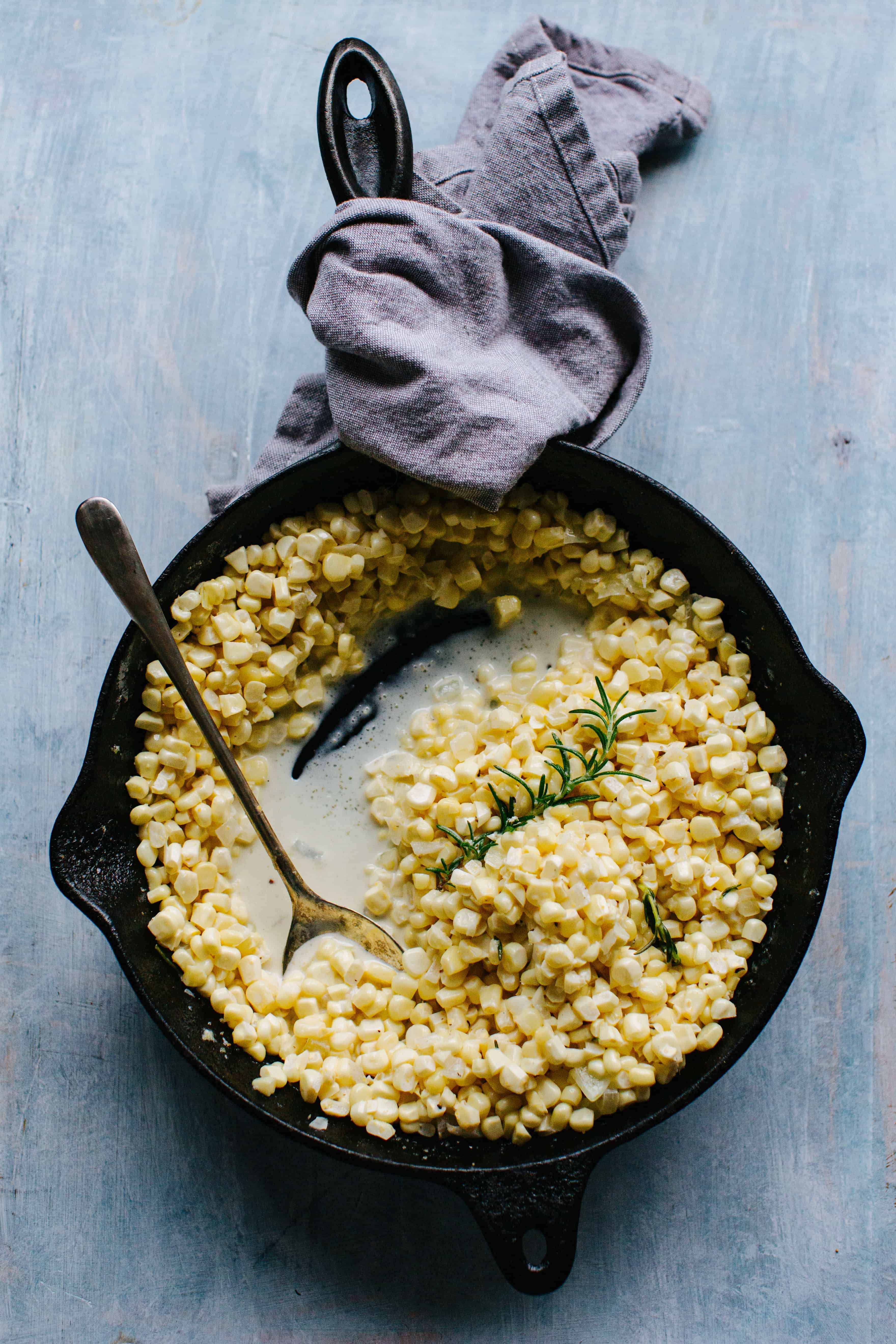 rosemary creamed corn in the pan with a spoon