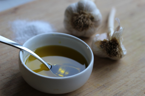 A spoon in a small white bowl of olive oil.