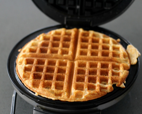 A fully baked waffle sitting in a waffle iron.