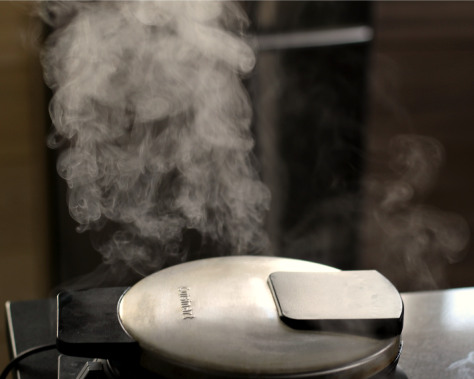 Steam escaping a stainless steel waffle iron.