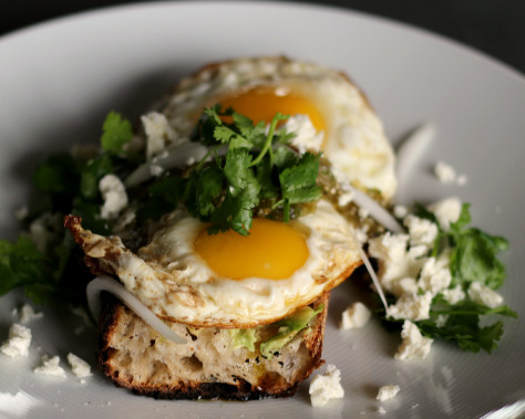 Close up of fried eggs on a slice of toasted baguette.