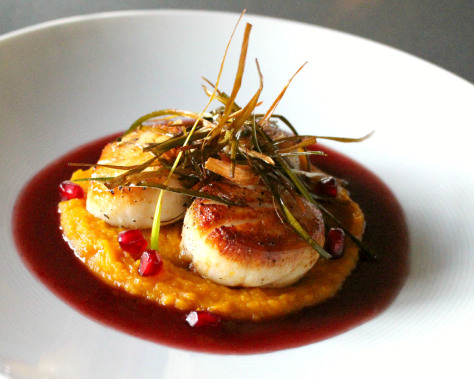 Three seared scallops on top of pomegranate beurre blanc.
