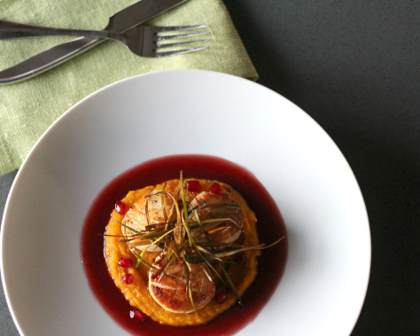 Top view of seared scallops on pomegranate beurre blanc.