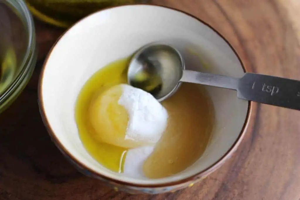 A small bowl containing an egg yolk, sugar, olive oil, and a spoon.