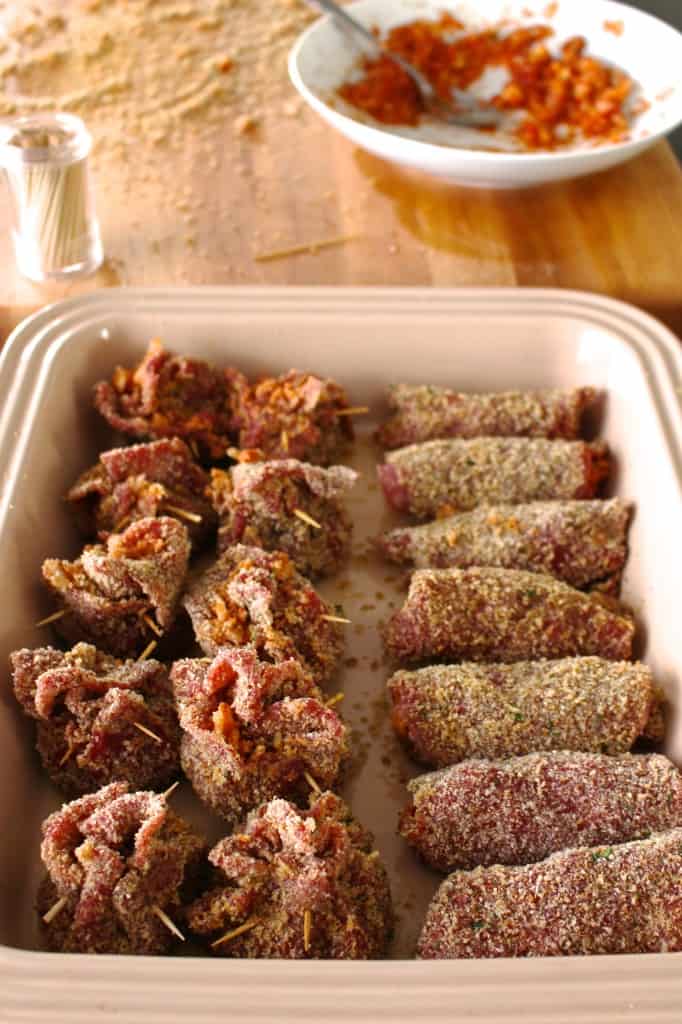 Baking dish filled with both rolled and bundled beef steak and tomato filling.