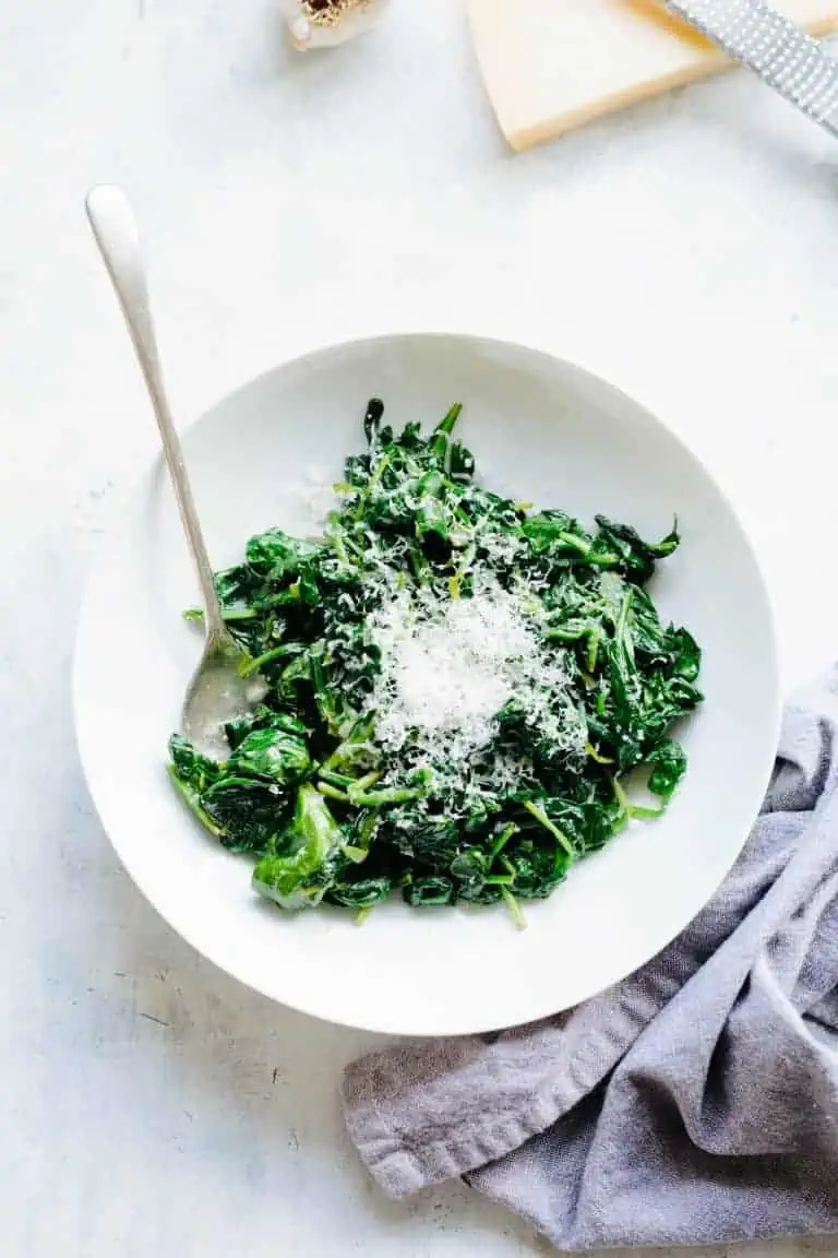 A serving of spinach with butter, topped with parmesan. 