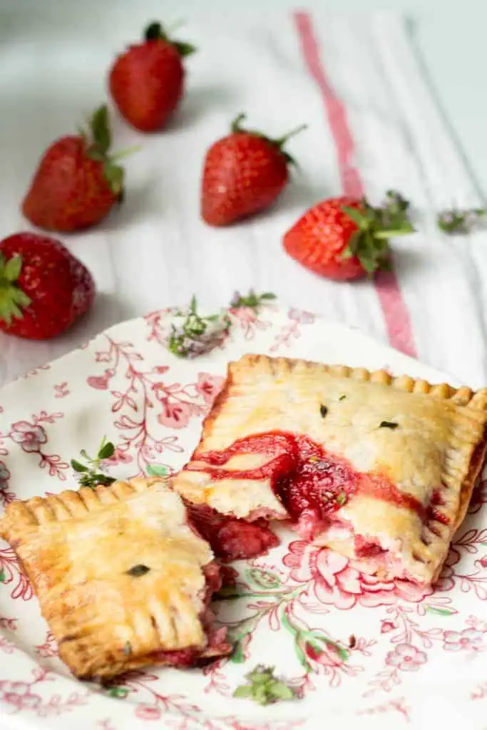 A strawberry goat cheese pop tart split in half on a floral plate.