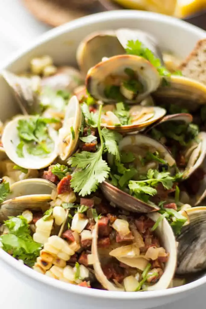 Close up of fresh baked clams that have been topped with fresh corn and crumbled chorizo.