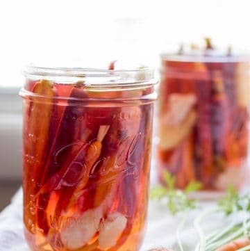 Side view of two pint mason jars filled with pickled carrots and garlic cloves.