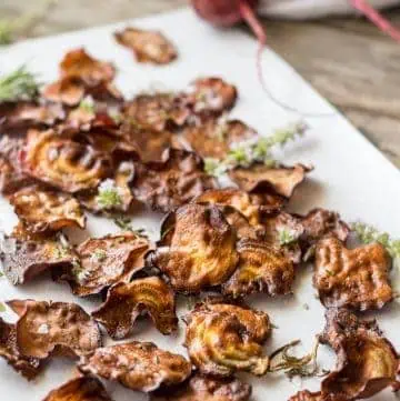 Top view of oven baked beet chips on a white platter.