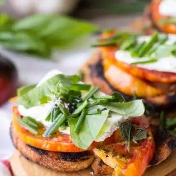 Heirloom tomatoes and feta on grilled toasts and garnished with fresh herbs.