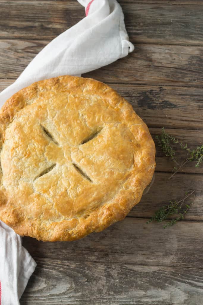 Top view of a baked chicken pot pie on a wood tabletop.