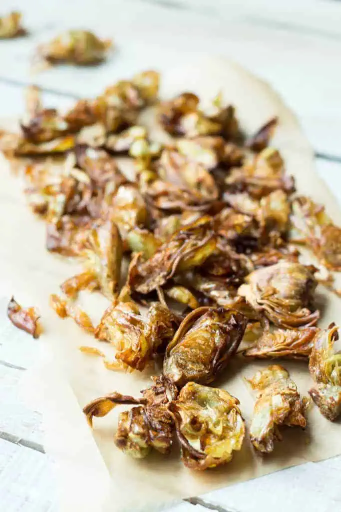 Fried artichokes drying on parchment paper.