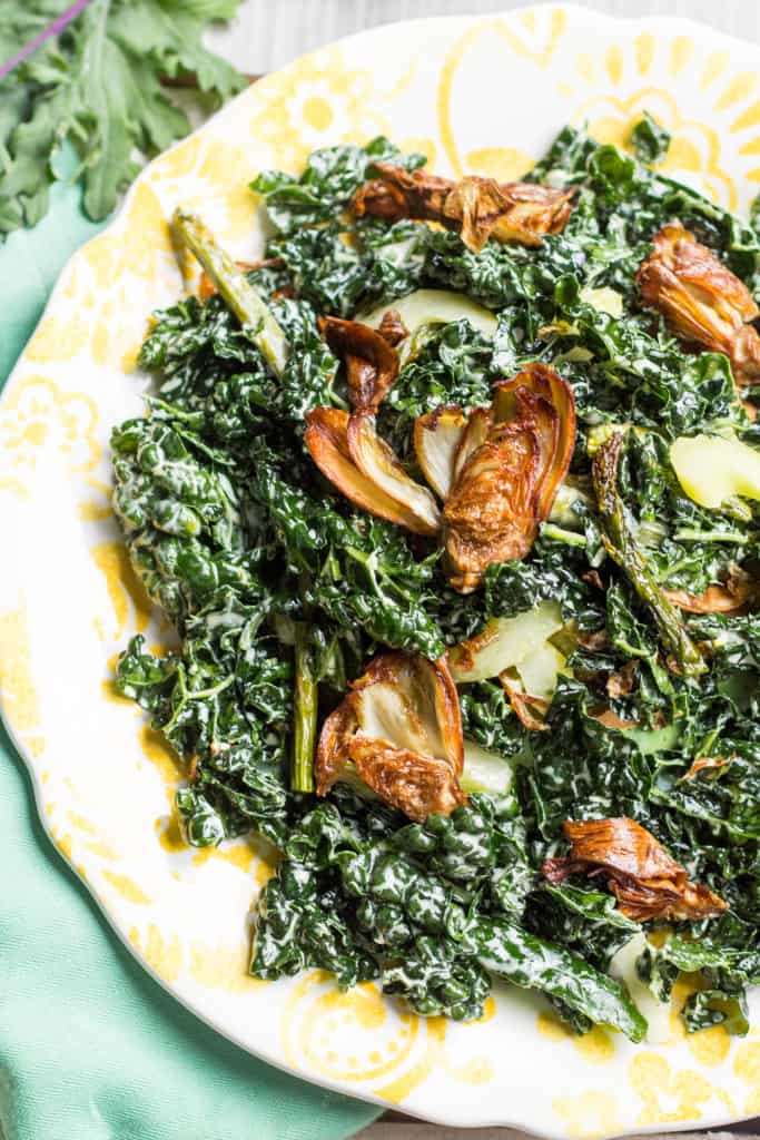 Top view of wilted kale salad topped with fried artichoke.