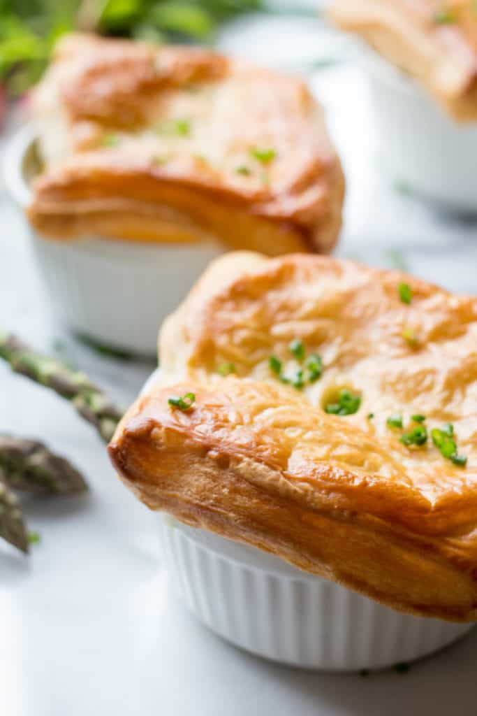 Close up of baked puff pastry over a ramekin of chicken pot pie filling.