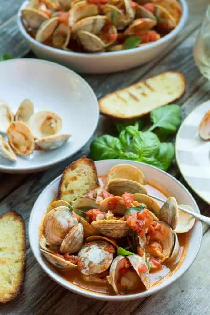 Dinner bowl of steamed clams with tomato and crostini.