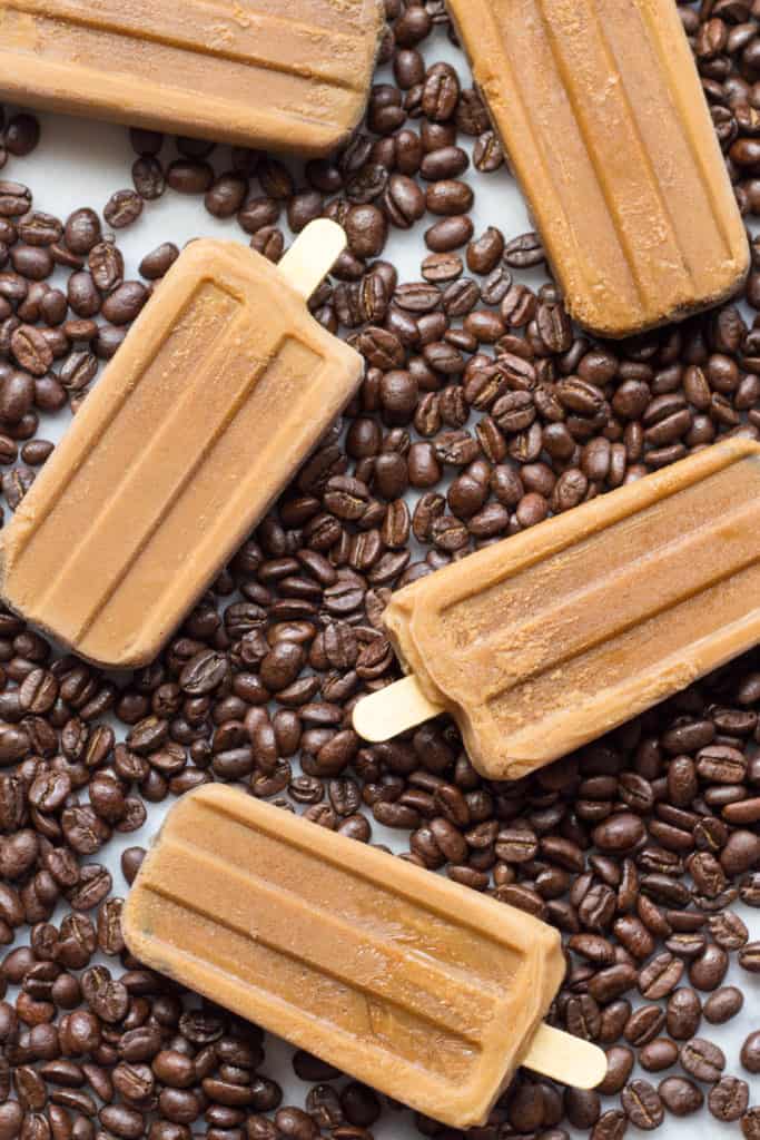 Top view of Vietnamese coffee popsicles on a coffee-bean-covered tabletop.