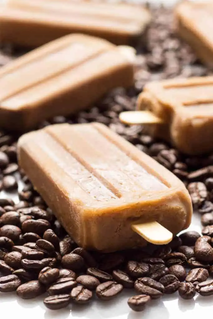 Close up of a Vietnamese coffee popsicle among coffee beans on a table.