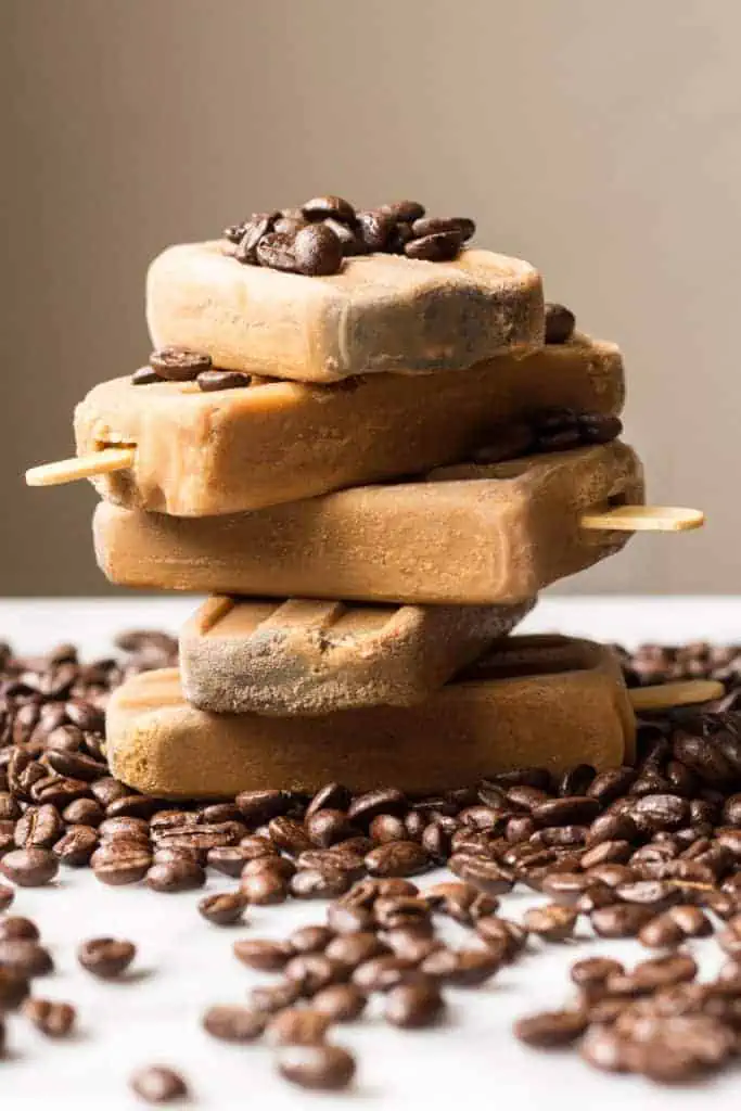 A stack of five Vietnamese coffee popsicles on a coffee bean-covered table.