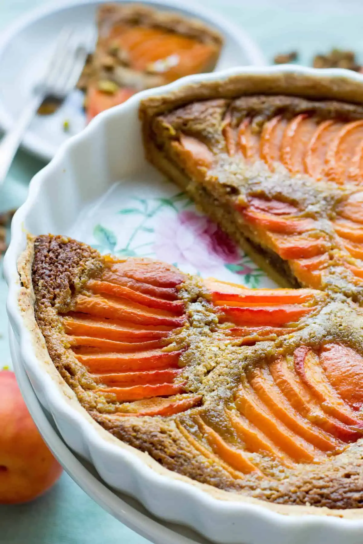 An apricot pistachio tart in a round baking dish with a slice missing.