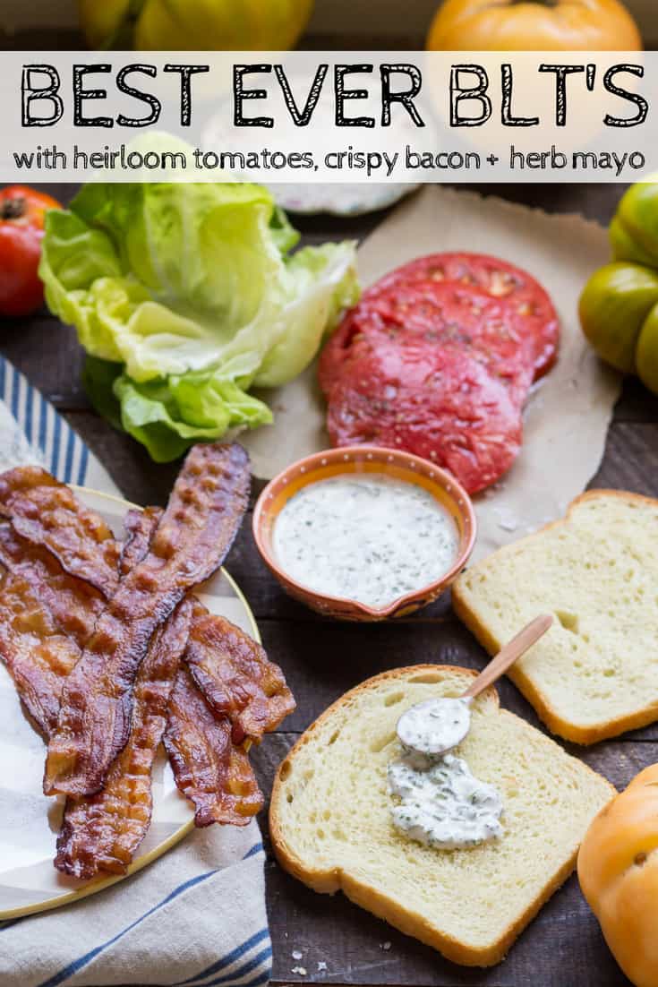 Spread of food on a table including lettuce, tomato slices, bacon, herb mayo, and bread slices.