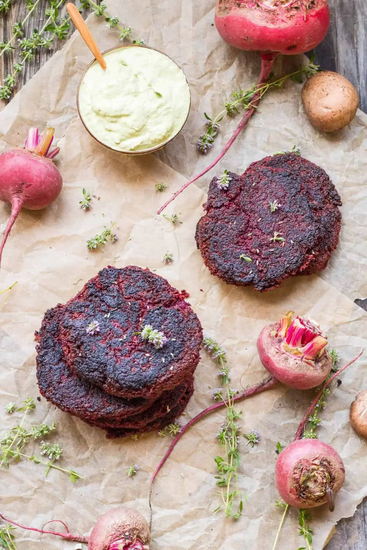 Stack of lentil beet burgers on parchment paper surrounded by fresh beets.