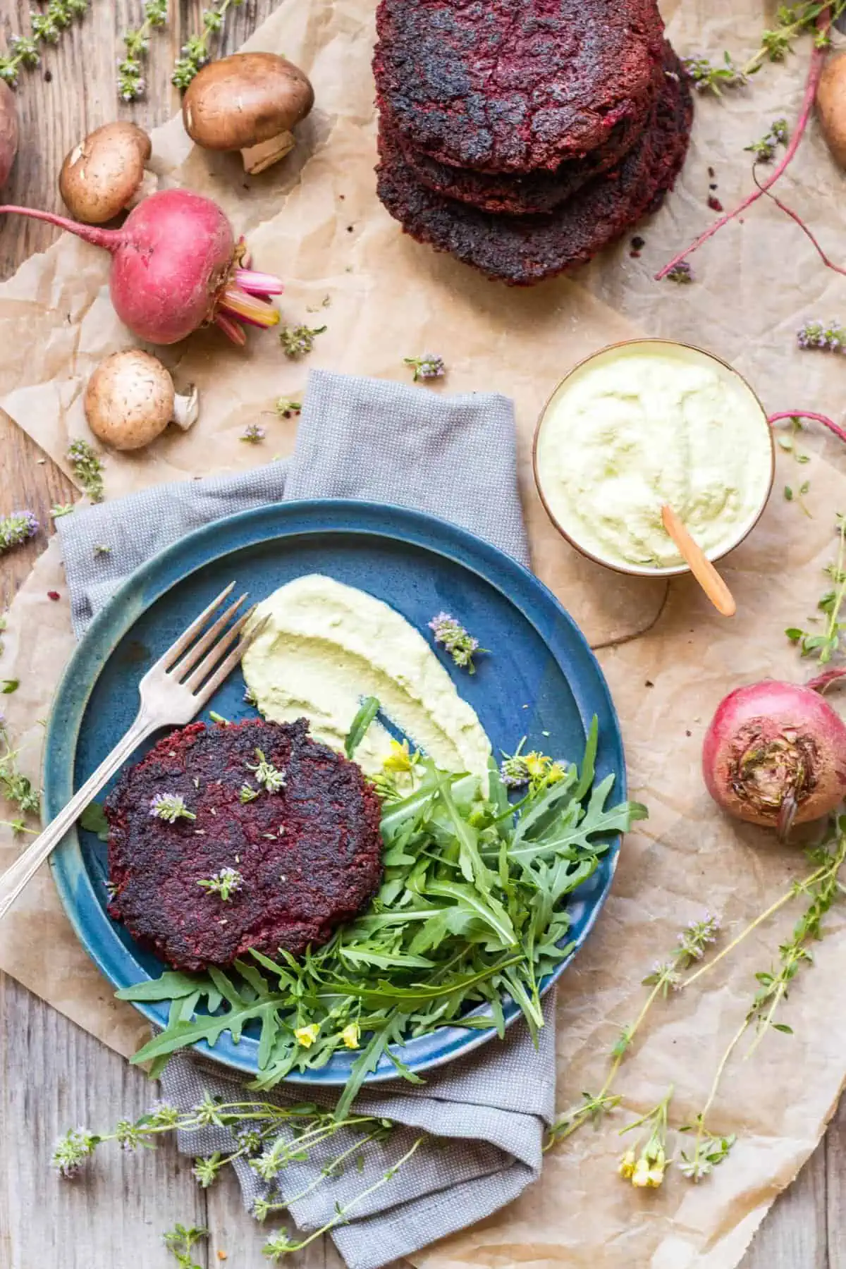 Top view of a blue dinner plate with a lentil beet burger and green salad.