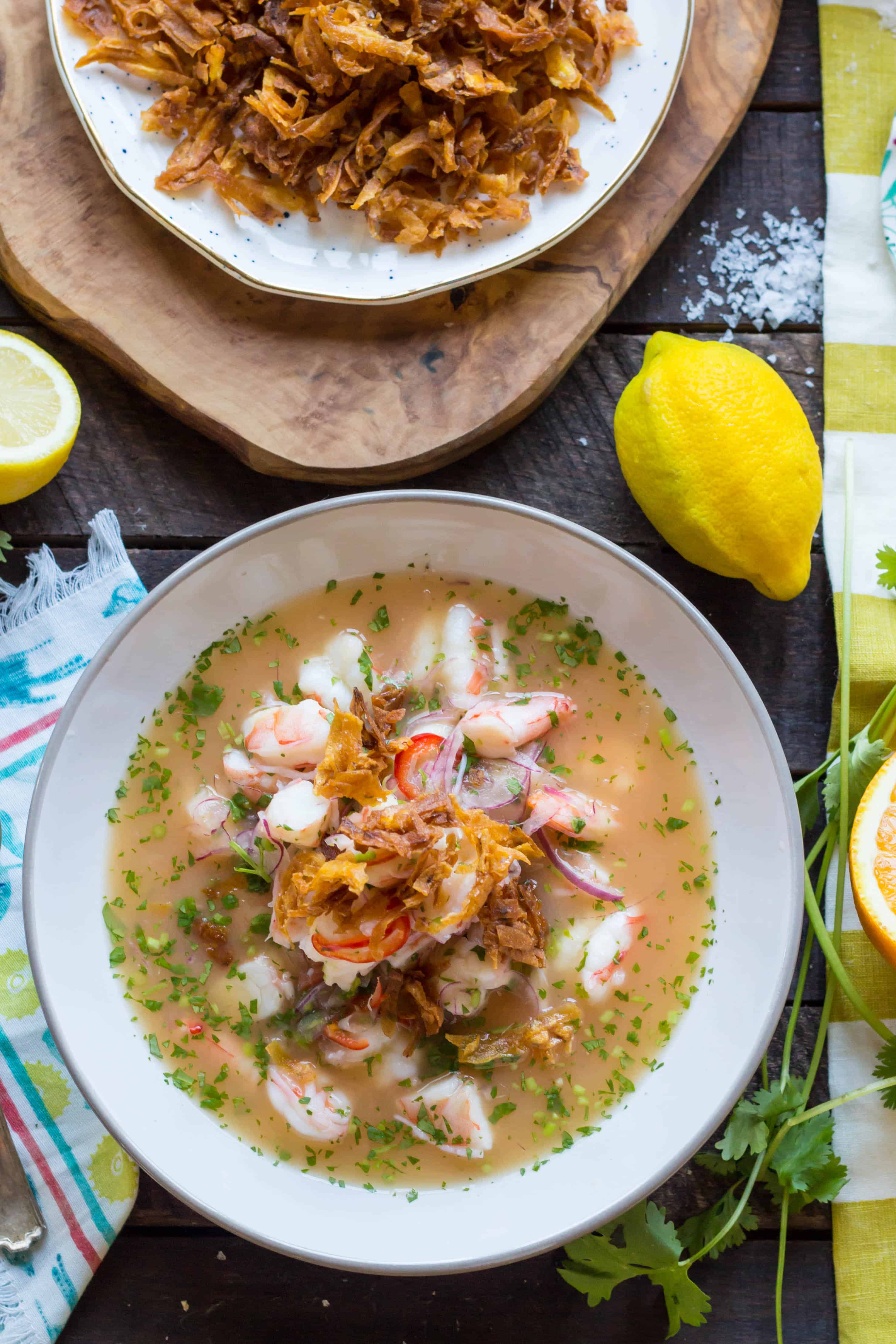 Top view of a soup bowl filled with shrimp ceviche topped with fried shallots.