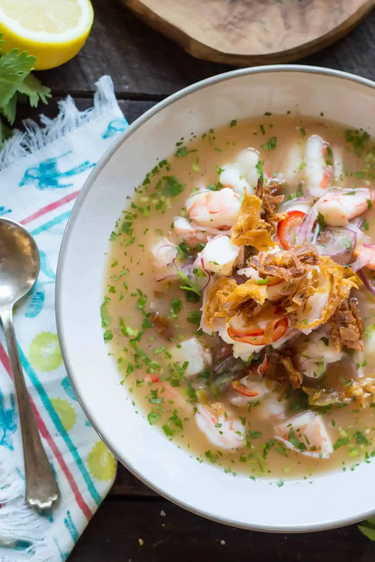 Top view of a white bowl of shrimp ceviche garnished with fried shallots.