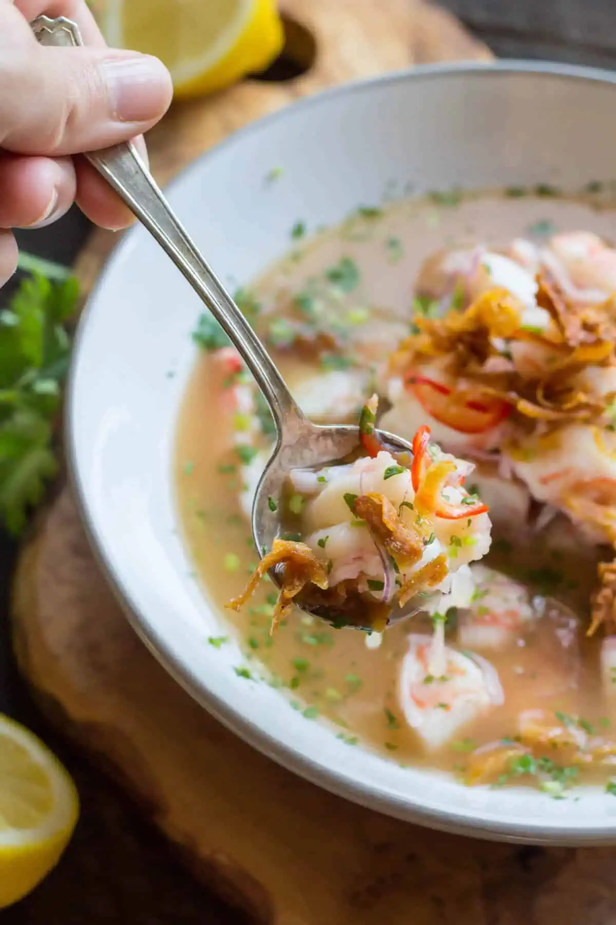 A spoon of shrimp ceviche over a soup bowl.