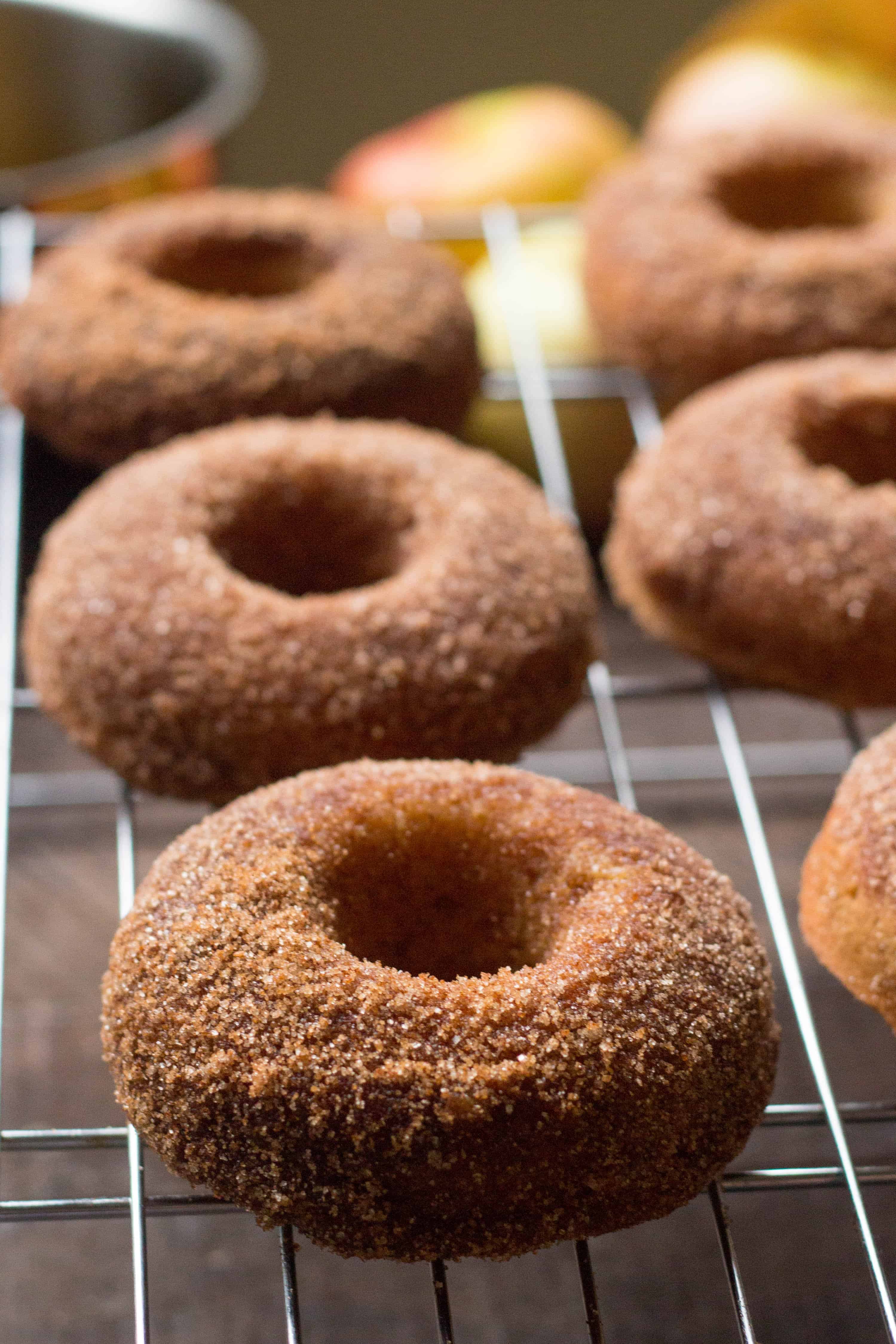 close up of apple cider doughnuts on a rack over a brown wood table