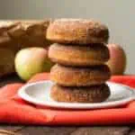 Vertical stack of four baked apple cider doughnuts on a small plate.