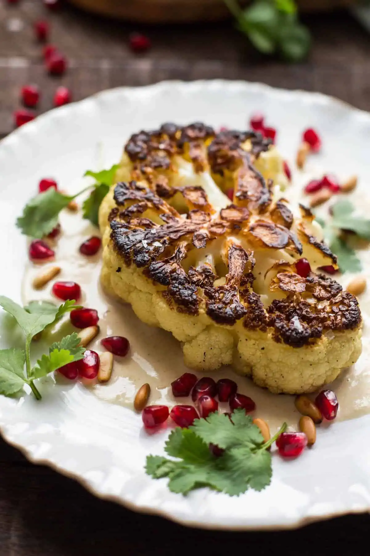 Close up of a grilled cauliflower steak on a white diner plate.