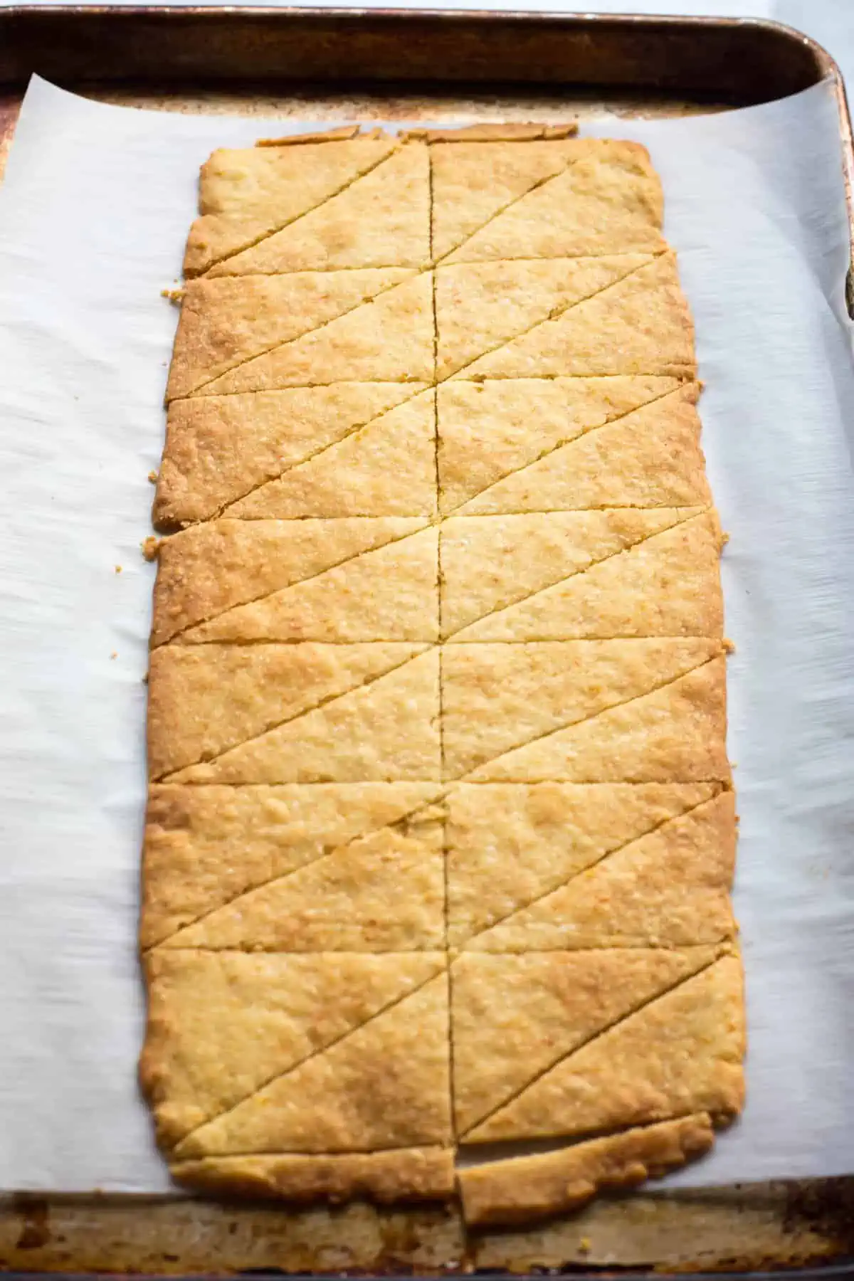 Baked cookie dough in a large rectangle cut into smaller triangles.