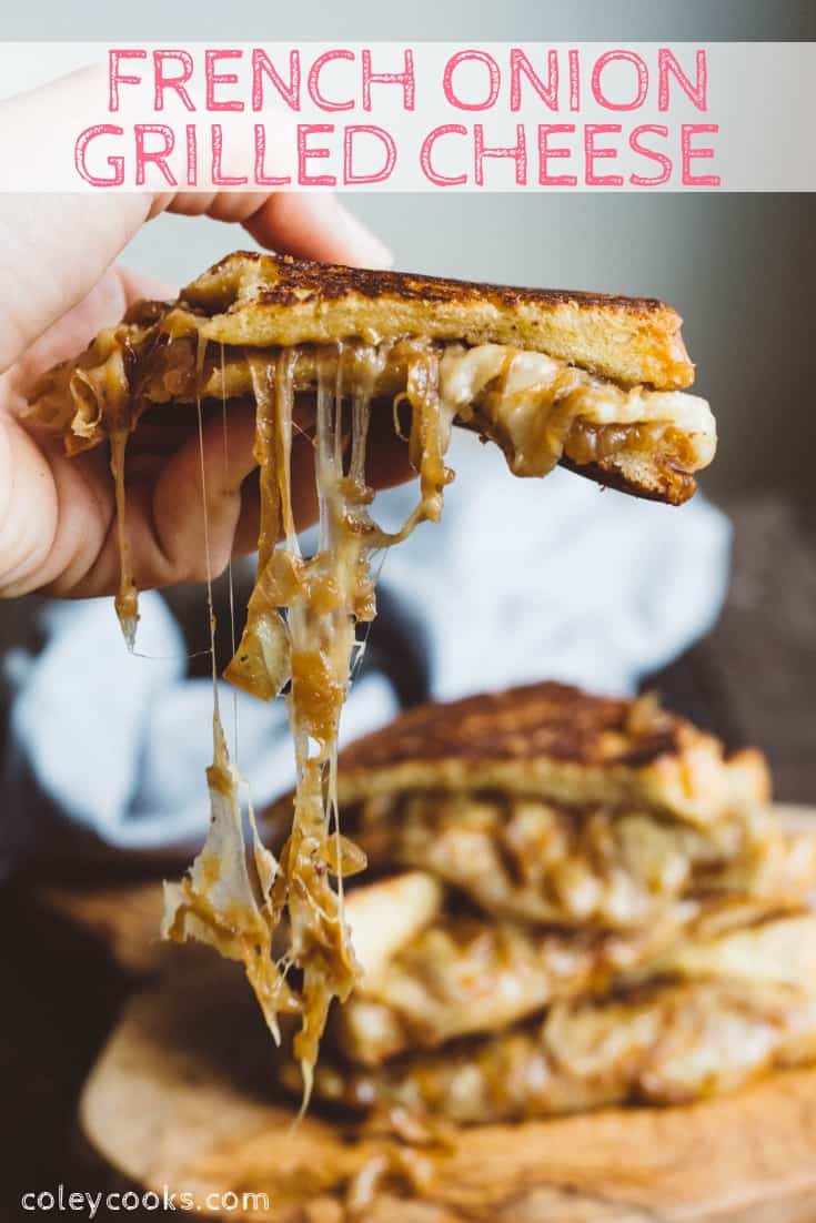 A hand holding half a french onion grilled cheese sandwich with cheese stringing out of it.