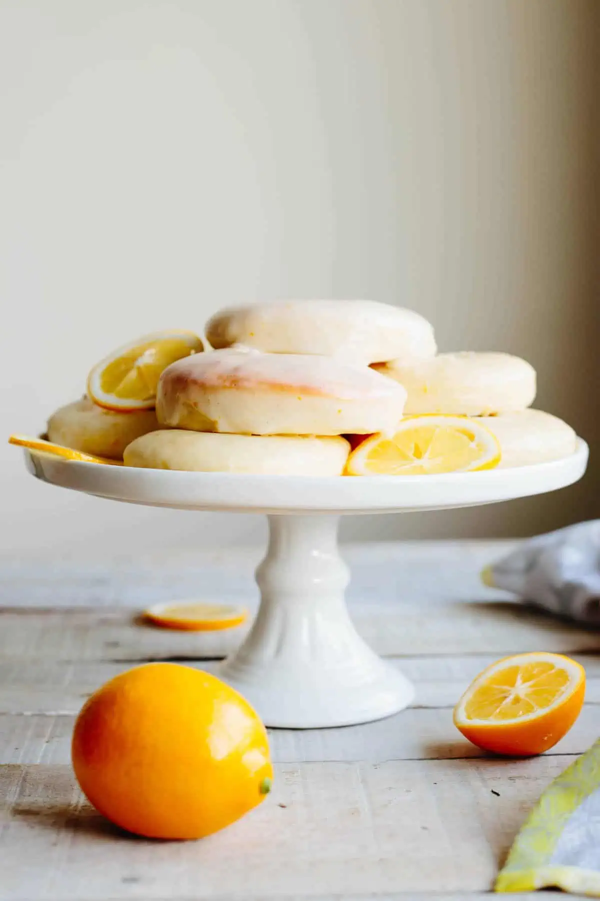 Baked lemon doughnuts stacked on a white cake stand.