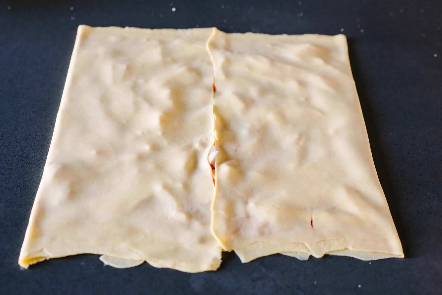 Bread dough folded over pizza sauce and mozzarella to make layers.
