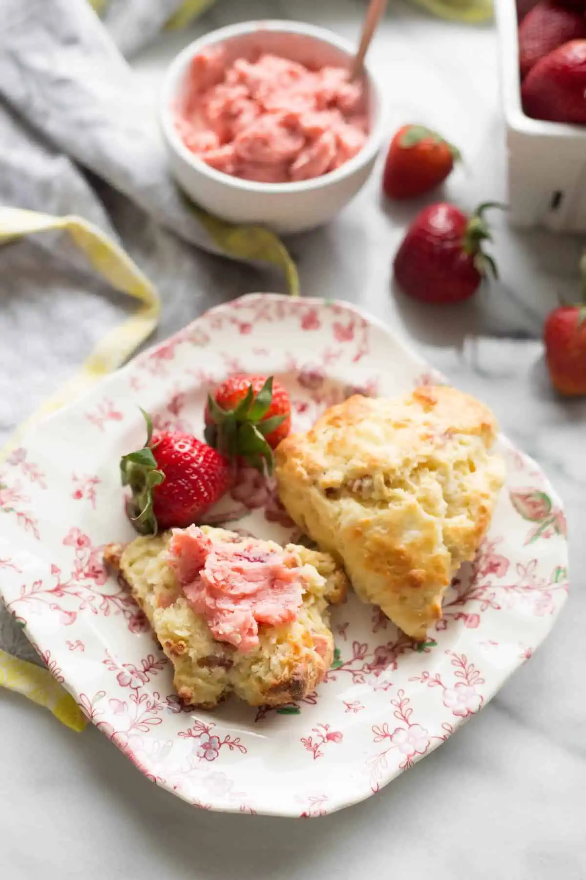 Square floral plate with two scones and fresh whole strawberries.