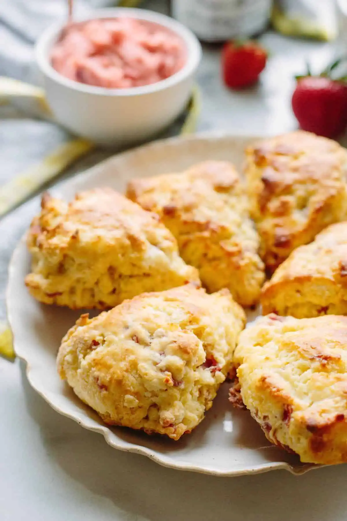 Prosciutto goat cheese scones arranged in a full circle on a white plate.