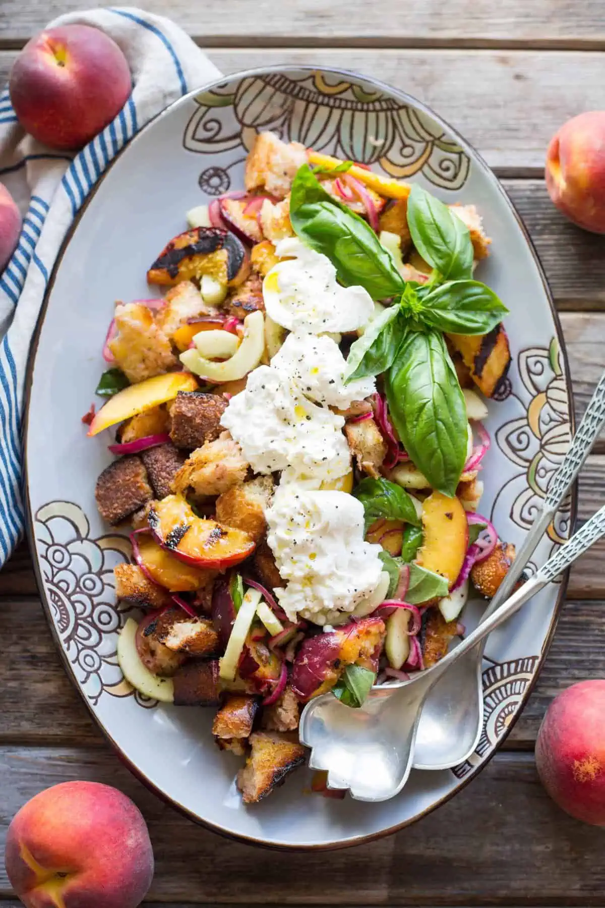 Oval serving platter with grilled peach panzanella and burrata.