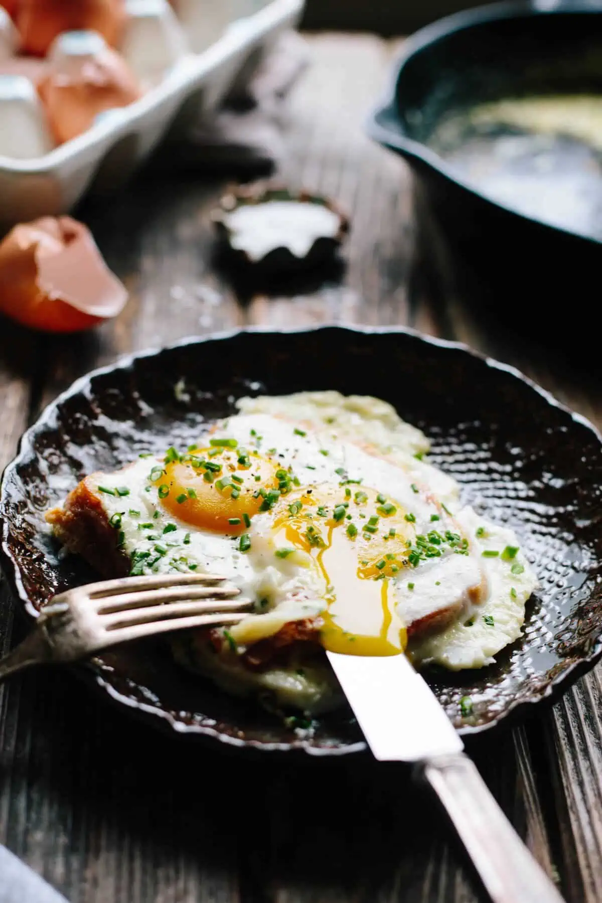 Baked eggs and French toast on a shallow bowl with fork and knife.