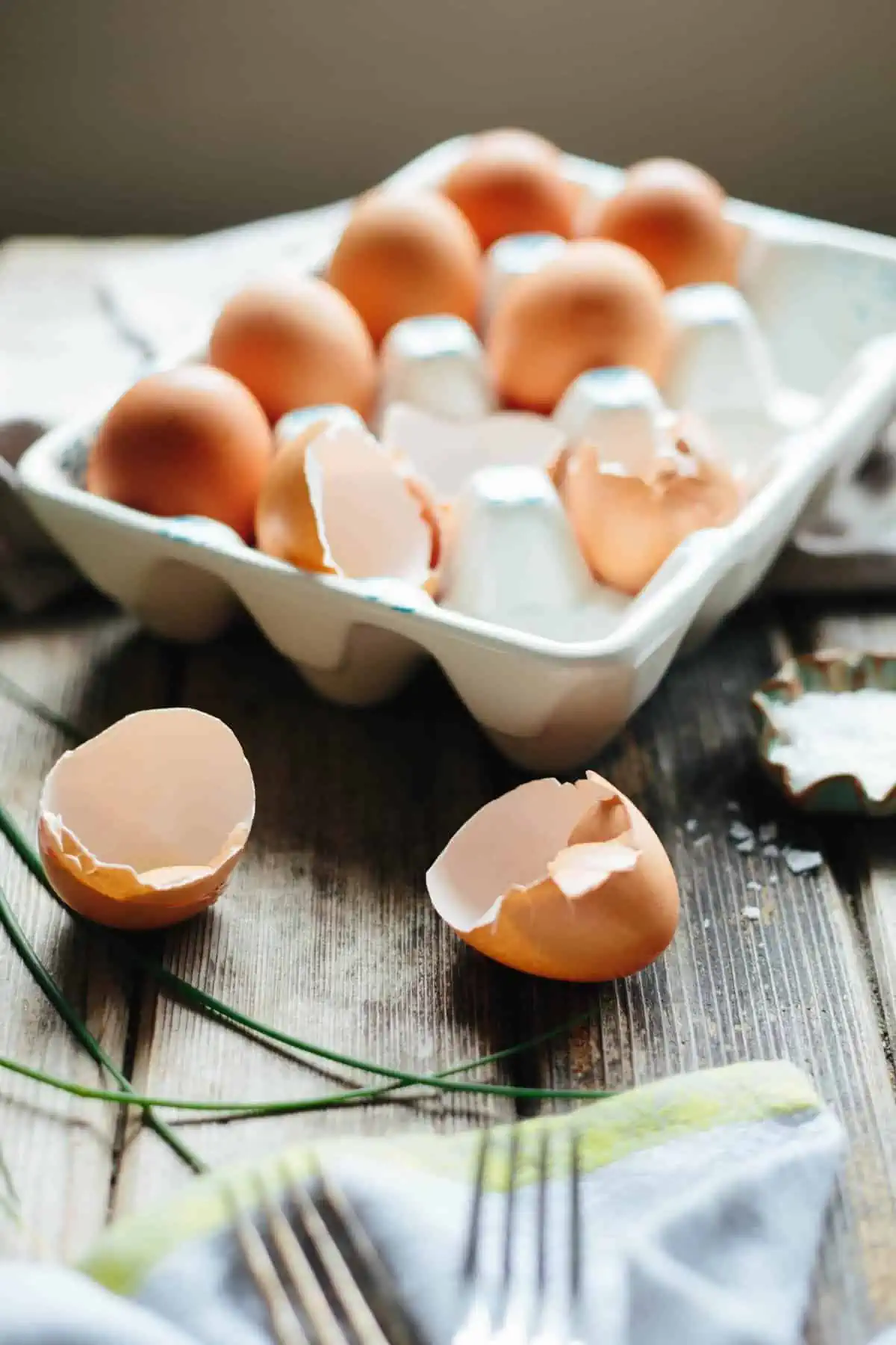 An egg carton with whole eggs and empty shells.