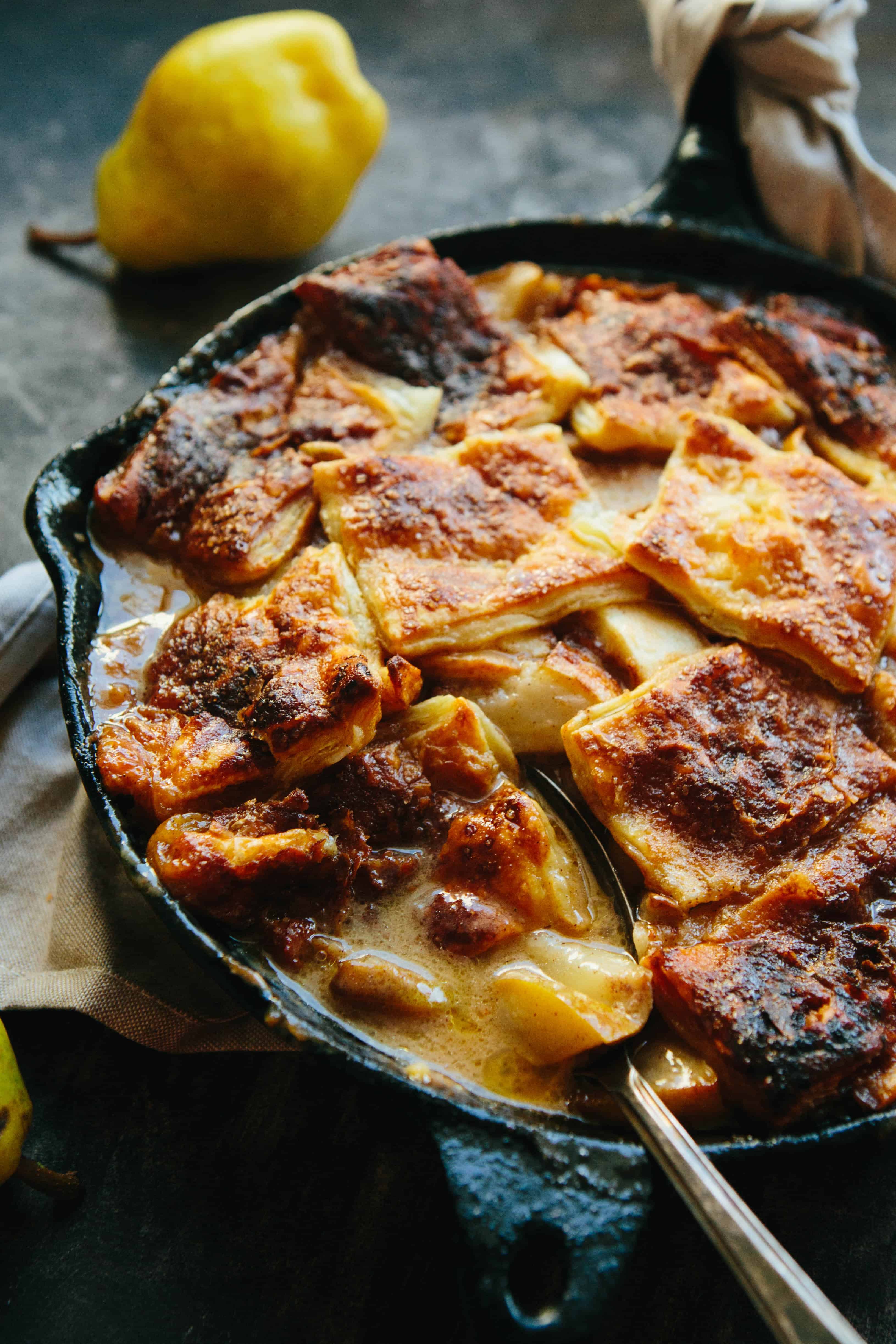 Baked pear pan dowdy in a cast iron skillet with a serving spoon digging in.