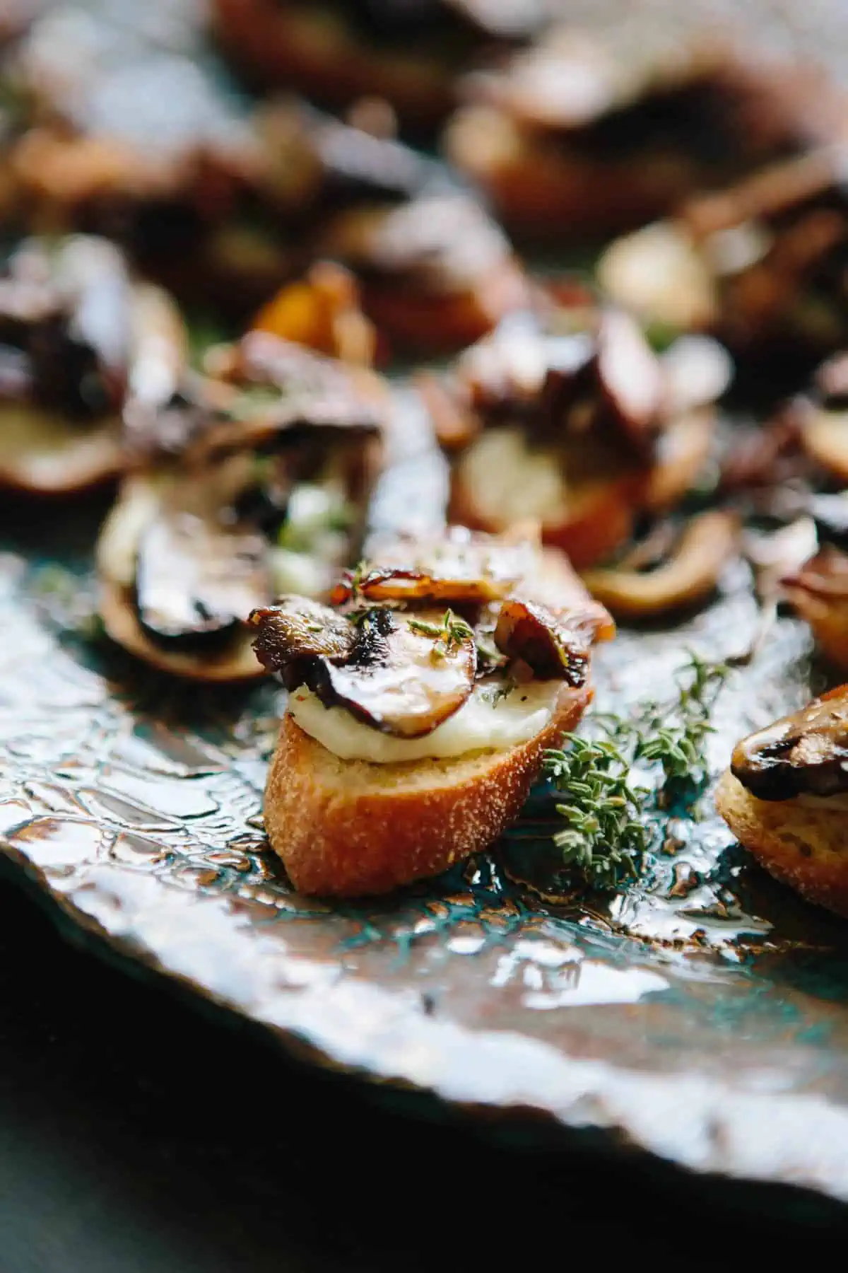 Close up of mushroom and cheese on crostini on a serving platter.