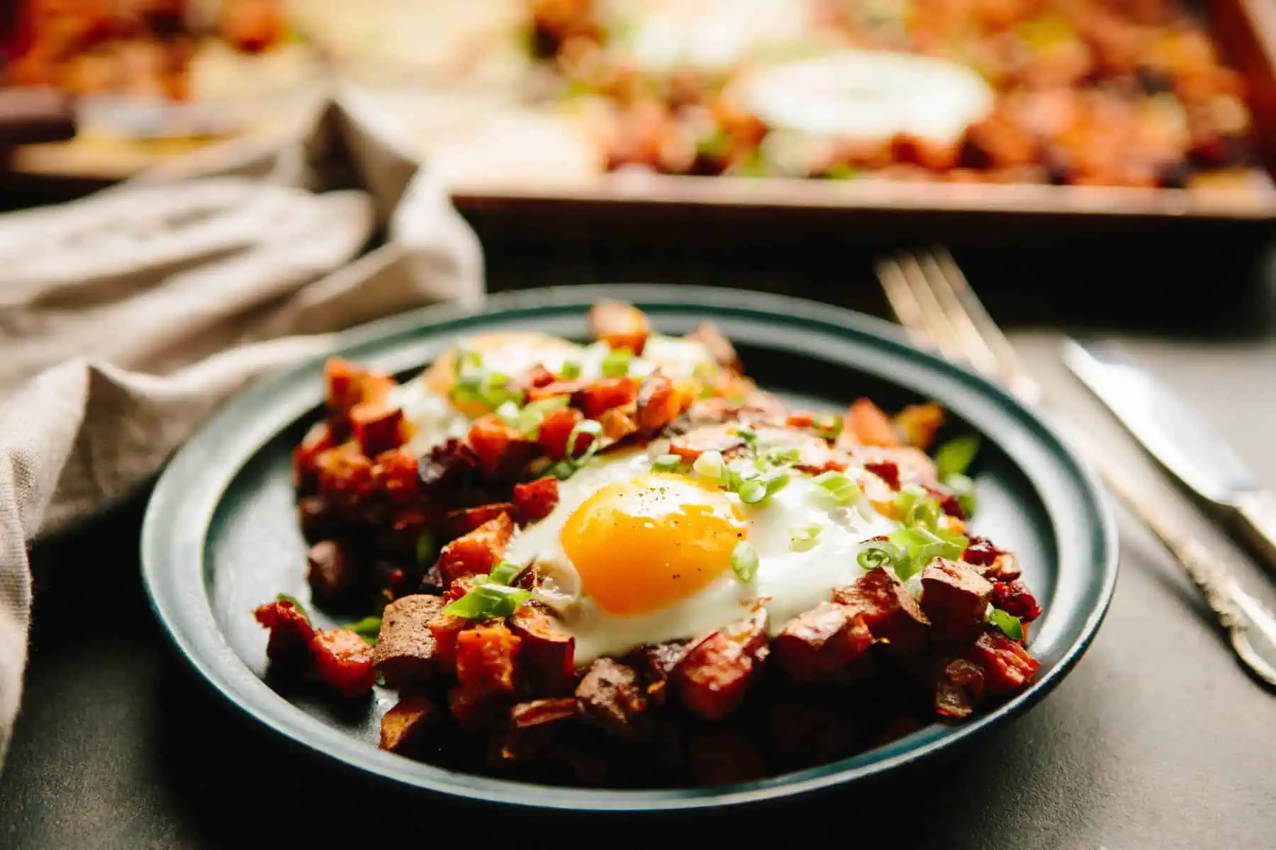 Dinner plate filled with sweet potato chorizo hash and runny eggs.