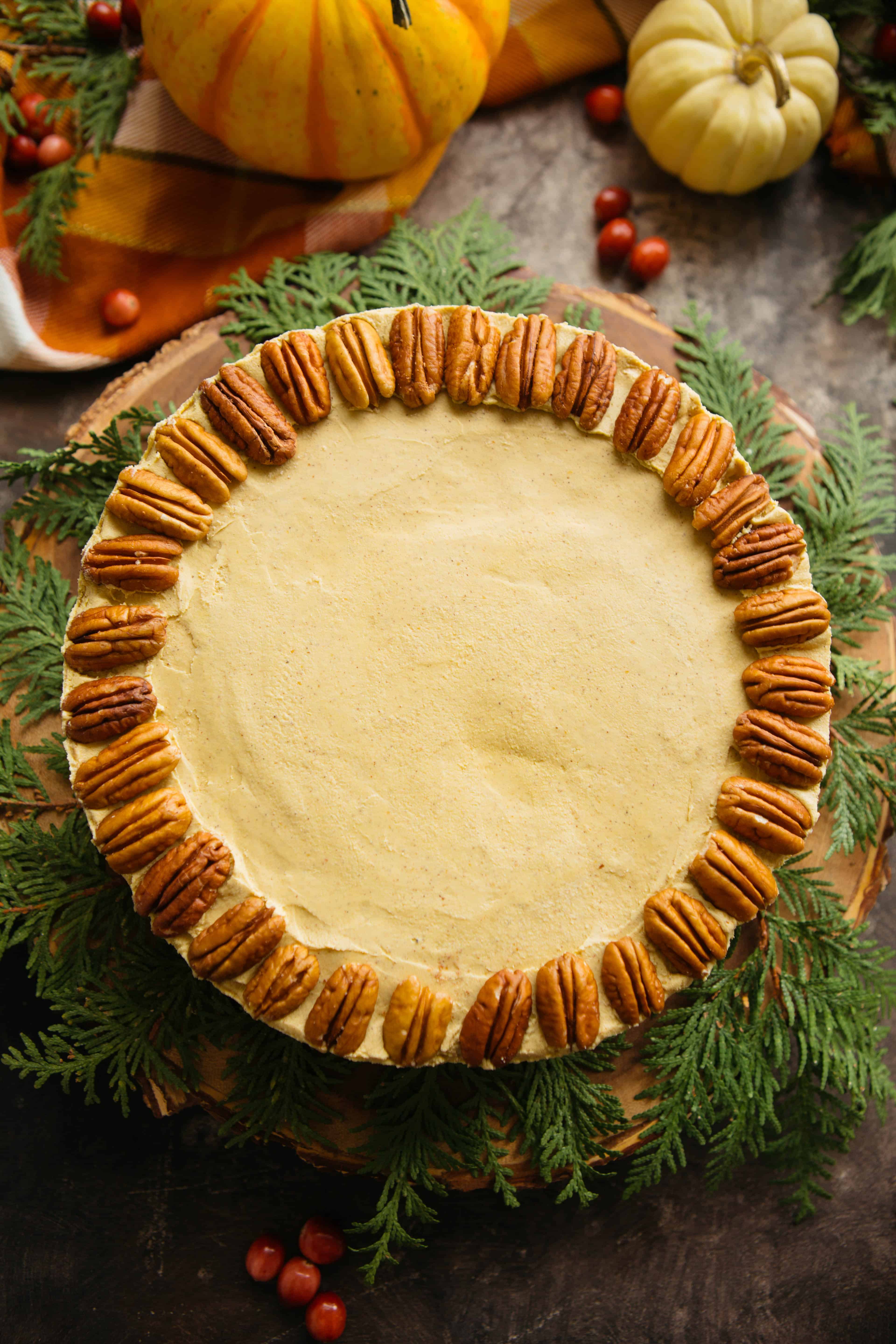 Top view of vegan pumpkin cheesecake with pecan halves set around the top edge.