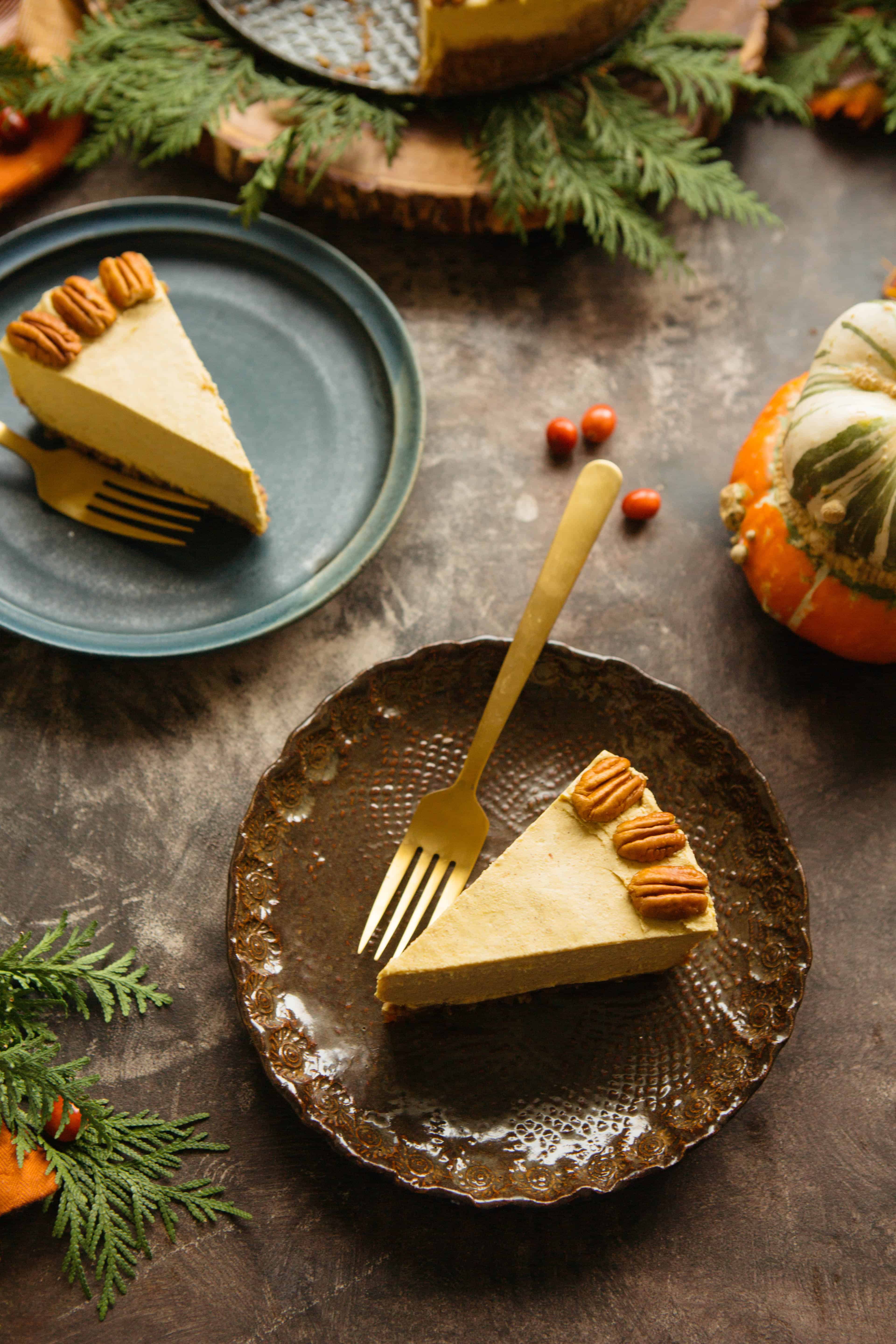 Two dessert plates, each with a fork and slice of vegan pumpkin cheesecake.